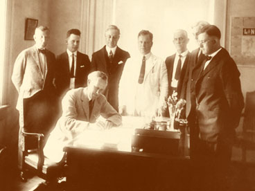 Florida Govenor Carey A. Hardee (seated) singing bill which established Collier County on May, 1923.  Barron Collier shown thrid from right, standing behind the Governor.
