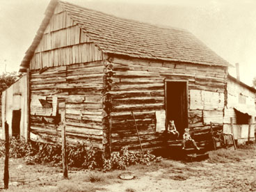 Log building believed to be a home in Immokalee with two unidentified boys in doorway. ( Circa 1920's)