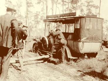 Naples-Fort Myers Transportation Company bus in the one-lane oyster shell road that connected Naples and Fort Myers in the early 1920's.  5 unidentified male passengers chopping log brace.  (John Hachmeister Collection)